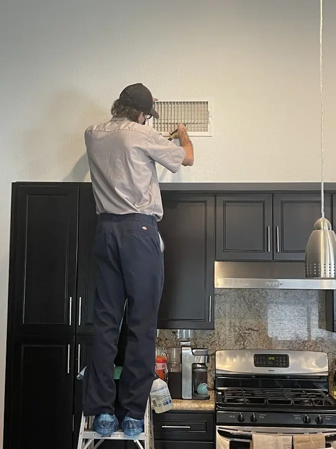 Technician inspecting an air vent during HVAC service in Rockland